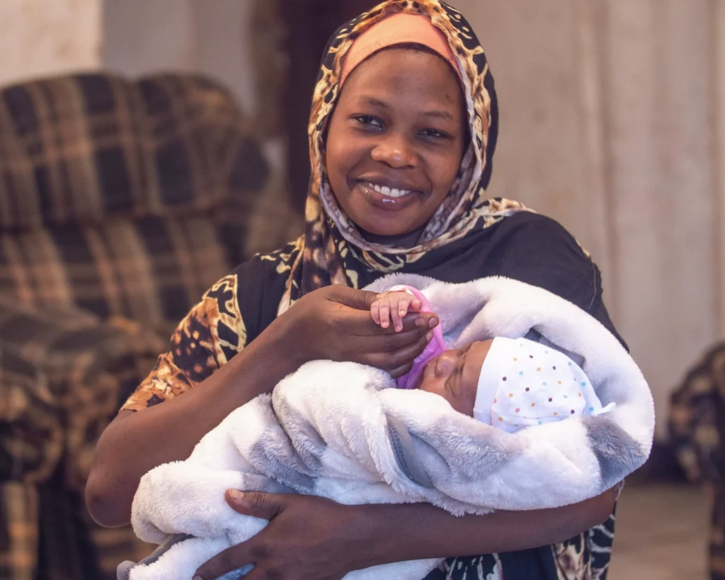 An image showing Tabu, one of the many mothers saved from postpartum hemorrhage thanks to the progra, holding her baby.